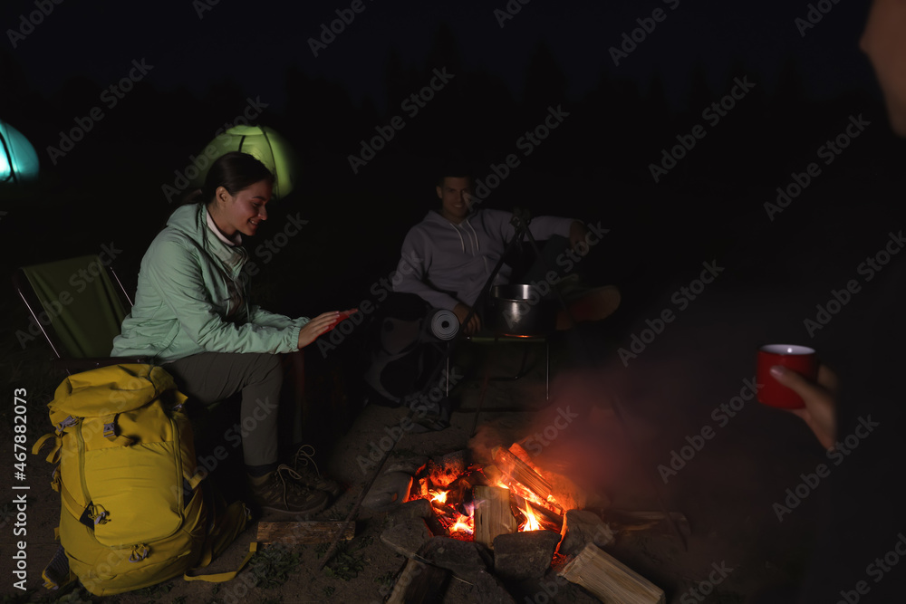 Obraz premium People sitting near bonfire in camp at night