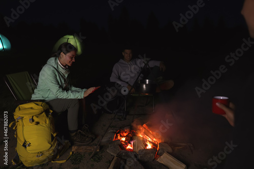 People sitting near bonfire in camp at night