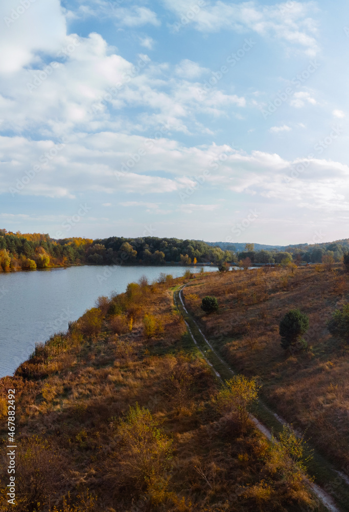 Aerial wide view of lake at sunrise in autumn. Meadows, orange grass, trees. Colorful landscape of river sunset. Horodok Ukraine Vertical photo