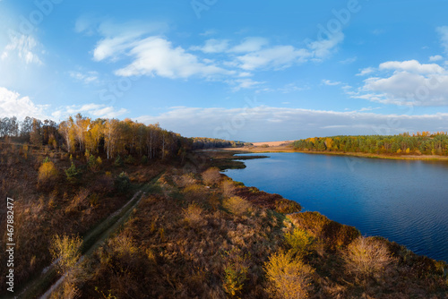 Fototapeta Naklejka Na Ścianę i Meble -  Aerial wide view of lake at sunrise in autumn. Meadows, orange grass, trees. Colorful landscape of river sunset. Horodok Ukraine