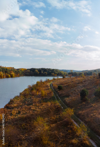 Aerial wide view of lake at sunrise in autumn. Meadows, orange grass, trees. Colorful landscape of river sunset. Horodok Ukraine Vertical photo