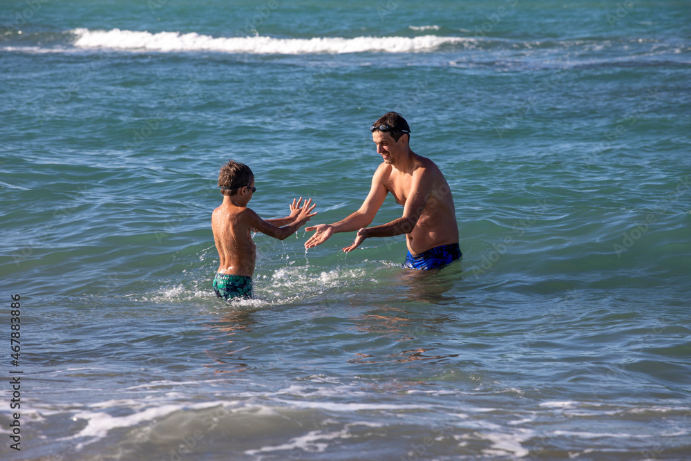 happy father with son playing in the sea on a sunny day, horizontal happy father with son playing in the sea on a sunny day, horizontal