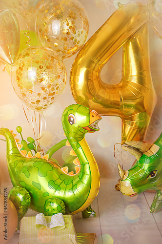Room decorated for a birthday party with golden, green and yellow baloons, large inflatable number 4, Dinosaur baloons.