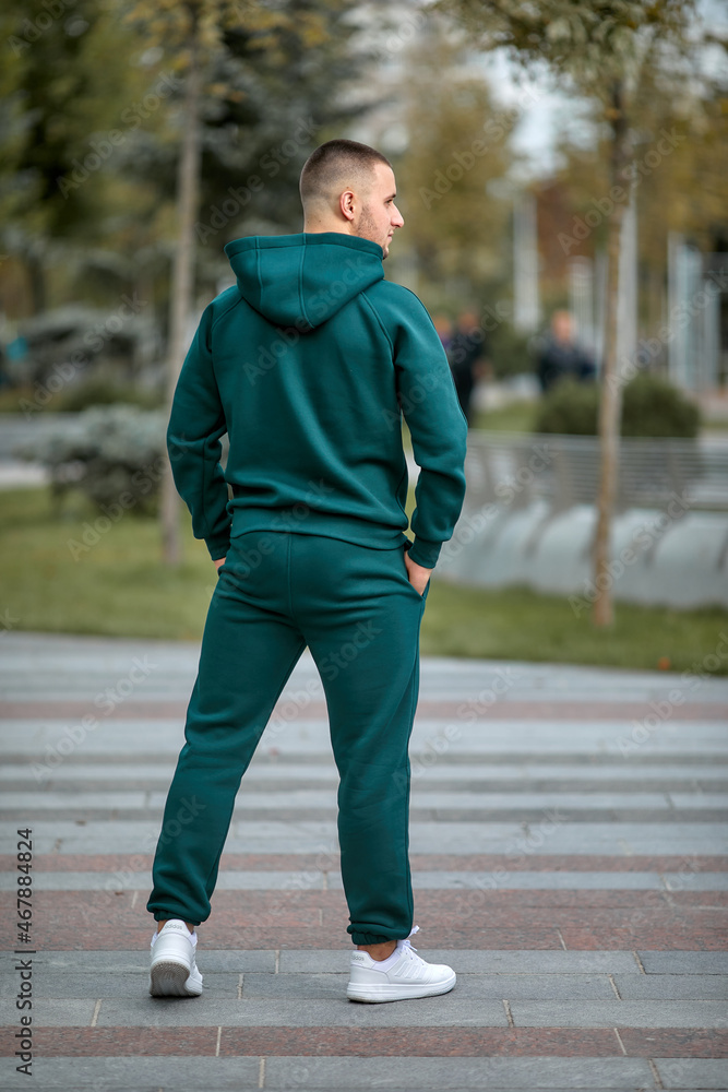 A young man in a tracksuit stands in a city park A young man in a tracksuit stands in a city park