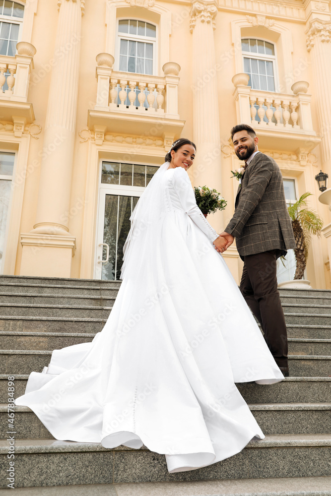 Fototapeta premium Young bride and groom on stairs outdoors, low angle view. Wedding couple