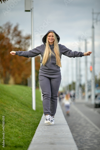 A young girl in a tracksuit stands in a city park