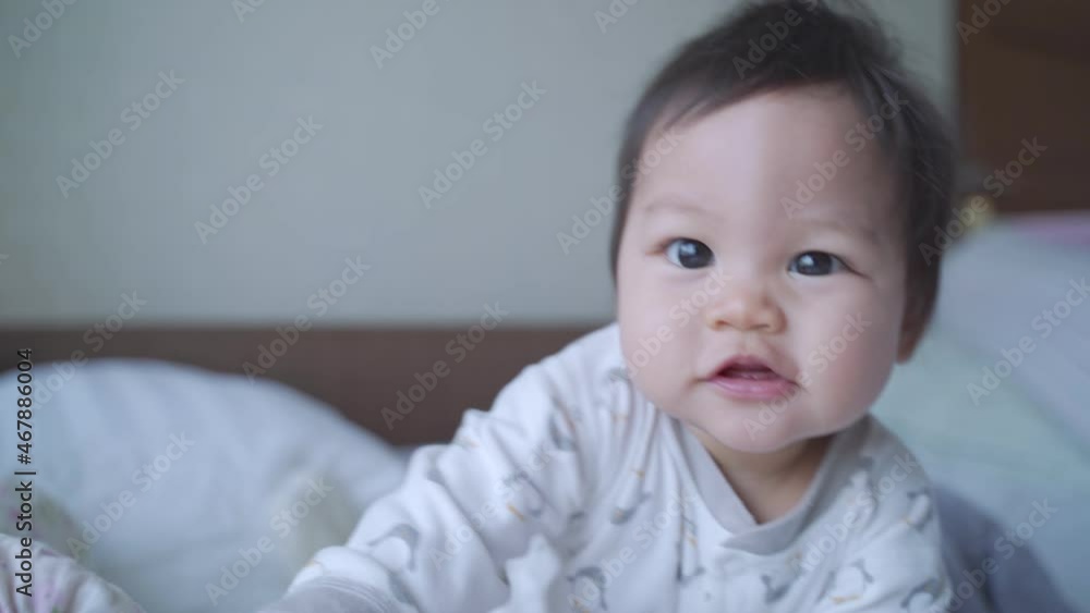 asian baby infant crawling on bed and looking at camera then happy smile. innocence kid smiling and fun enjoy moment. baby toddler playful with funny face in bedroom at home. authentic life. asian baby infant crawling on bed and looking at camera then happy smile. innocence kid smiling and fun enjoy moment. baby toddler playful with funny face in bedroom at home. authentic life.