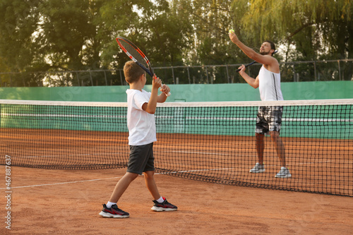 Father with his son playing tennis on court © New Africa