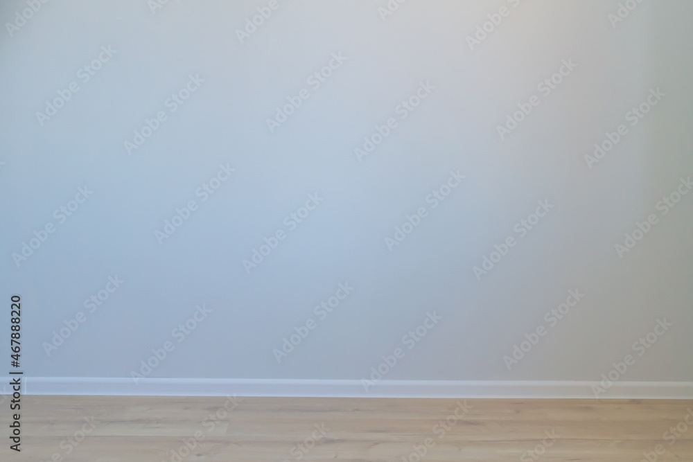 An empty gray wall and a beige background with a white baseboard. Background