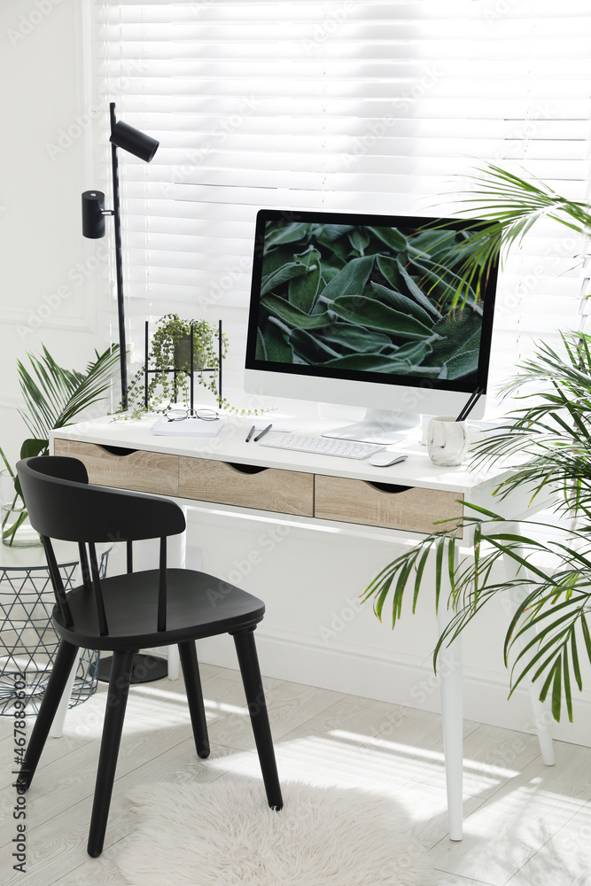 Fototapeta premium Comfortable workplace with modern computer and green plants in room. Interior design