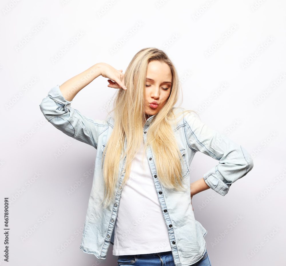 Young smiling blond woman with long hair wearing casual over light grey background. Young smiling blond woman with long hair wearing casual over light grey background.