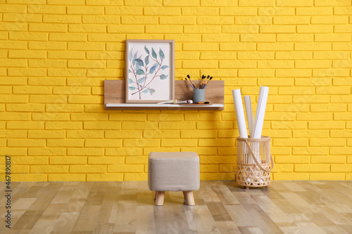 Stylish pouf near yellow brick wall indoors. Interior design