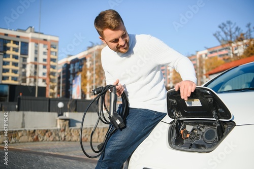 Man charges an electric car at the charging station © Serhii