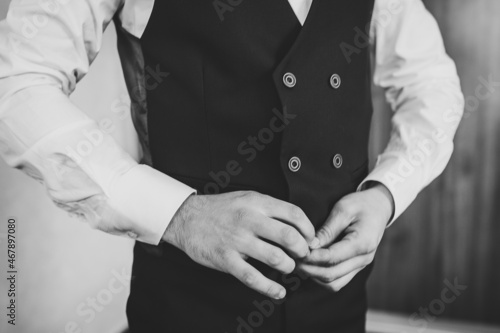 Man is buttoning his vest. close-up. Perfect to the last detail. Modern businessman. Fashion shot of a handsome young man in elegant classic suit. Men's beauty, fashion. Black and white photo. © Serhii
