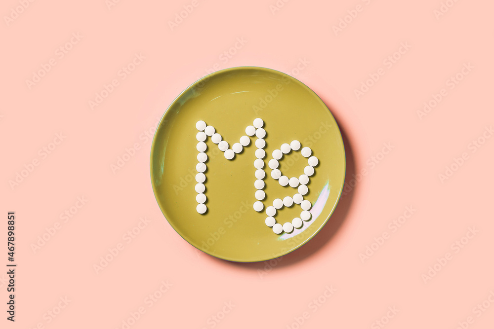 Pills with mineral Mg or magnesium on yellow plate. Mg inscription made of medical pills - obrazy, fototapety, plakaty 