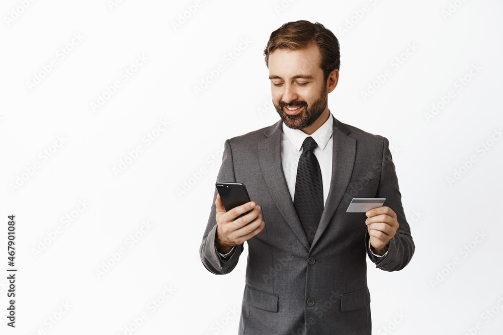Successful businessman using mobile phone and credit card, paying online, register in application on smartphone, white background Successful businessman using mobile phone and credit card, paying online, register in application on smartphone, white background