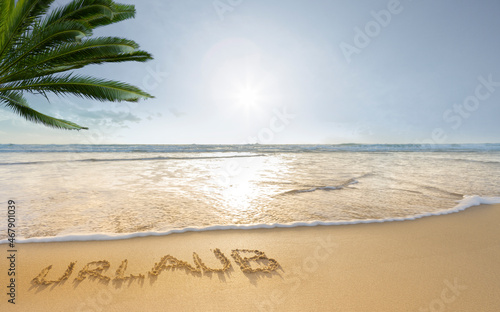 Das Wort Urlaub in den Sand geschrieben an einem Südseestrand
