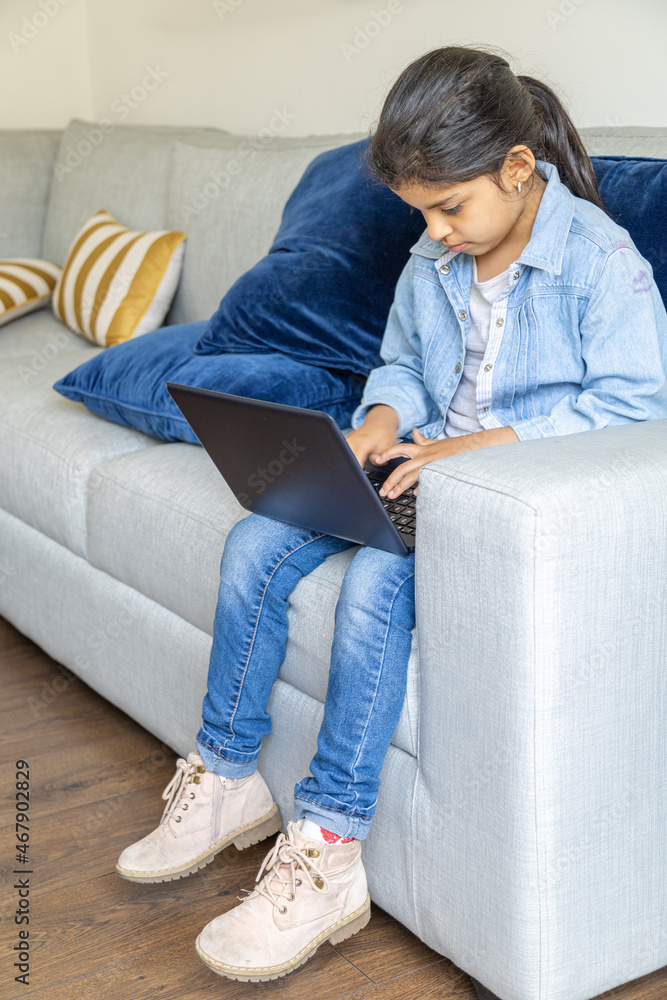 Young girl is using her laptop on the living room sofa Young girl is using her laptop on the living room sofa