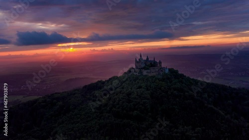 Aerial Forward Scenic View Of Hohenzollern Castle On Mountain, Drone Flying Over Forest photo