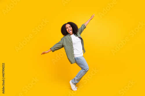 Full size photo of funny brunette young curves lady dance wear shirt jeans footwear isolated on yellow color background
