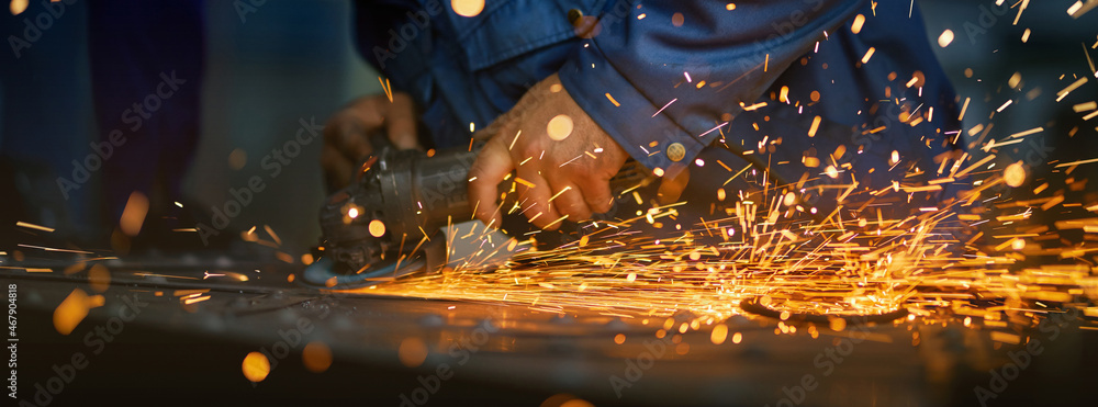 Close up of male hands using special tool for cutting metal at workshop. Sparks flying from metal processing. Craft production.  - obrazy, fototapety, plakaty 