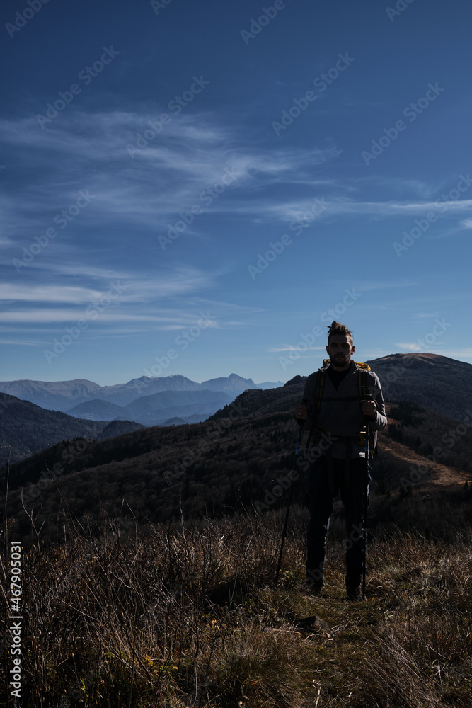 Good weather and tourists walk along famous trail in reserve. Caucasian young male traveler walks through mountains with large backpack and enjoys views of nature.