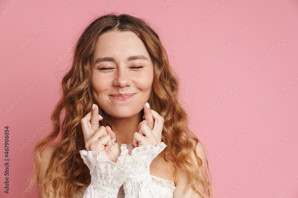 Young ginger woman smiling while holding fingers crossed for good luck Young ginger woman smiling while holding fingers crossed for good luck