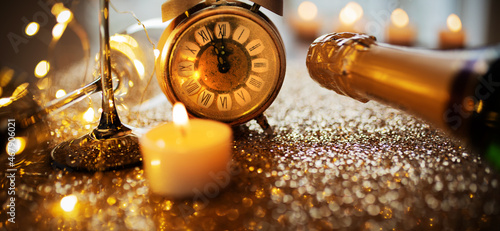 New year countdown with champagner on gold glittering surface with candlelight and bokeh, Horizontal background with short depth of field for new year congratulations.