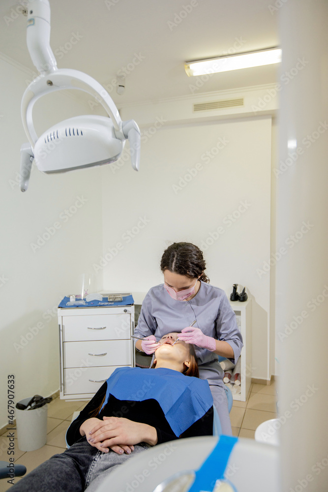 Female dentist checking up patient teeth at dental clinic office. Medicine, dentistry concept. Dental equipment Female dentist checking up patient teeth at dental clinic office. Medicine, dentistry concept. Dental equipment