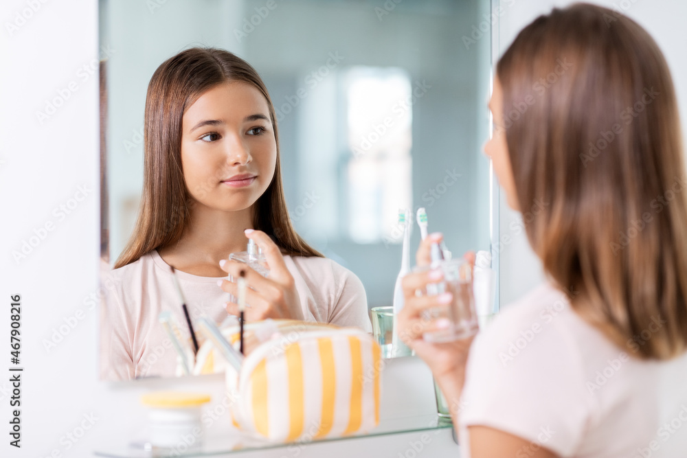 beauty, people and make up concept - teenage girl spraying perfume at home bathroom beauty, people and make up concept - teenage girl spraying perfume at home bathroom