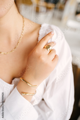 Woman's hand lies on a white shirt demonstrating gold jewelry
