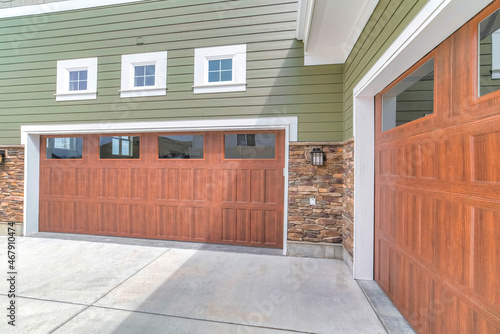 Wooden garage doors with window panels and wall lamp