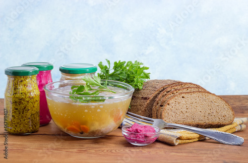 Pork jelly in glass bowl, different seasoning, bread and cutlery photo