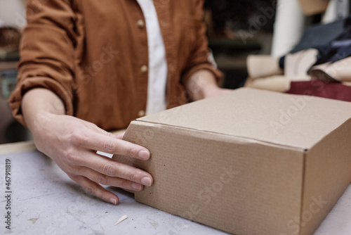 Close-up of delivery person packing box for customer in the workshop