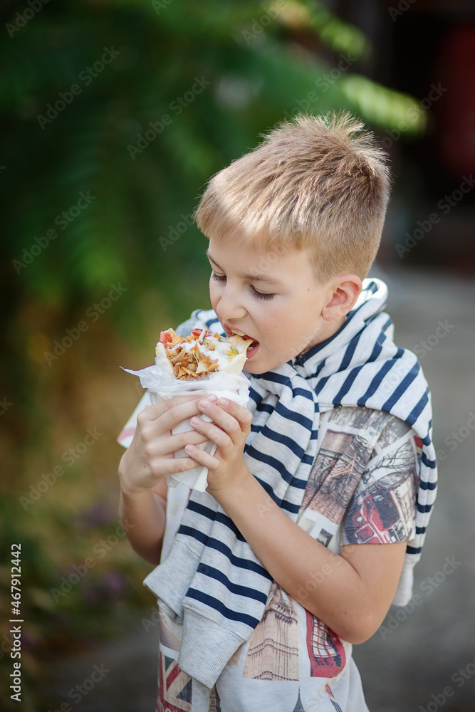 Cute blonde boy eating shrimp roll at fast food restaurant. Unhealthy meal for kids. Junk food. Cute blonde boy eating shrimp roll at fast food restaurant. Unhealthy meal for kids. Junk food.