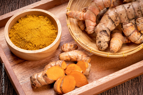 Turmeric Powder and Turmeric root in wooden plate, Curry Powder on a wooden table background.