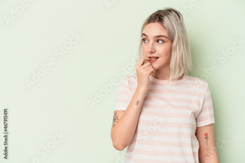 Young caucasian woman isolated on green background relaxed thinking about something looking at a copy space.