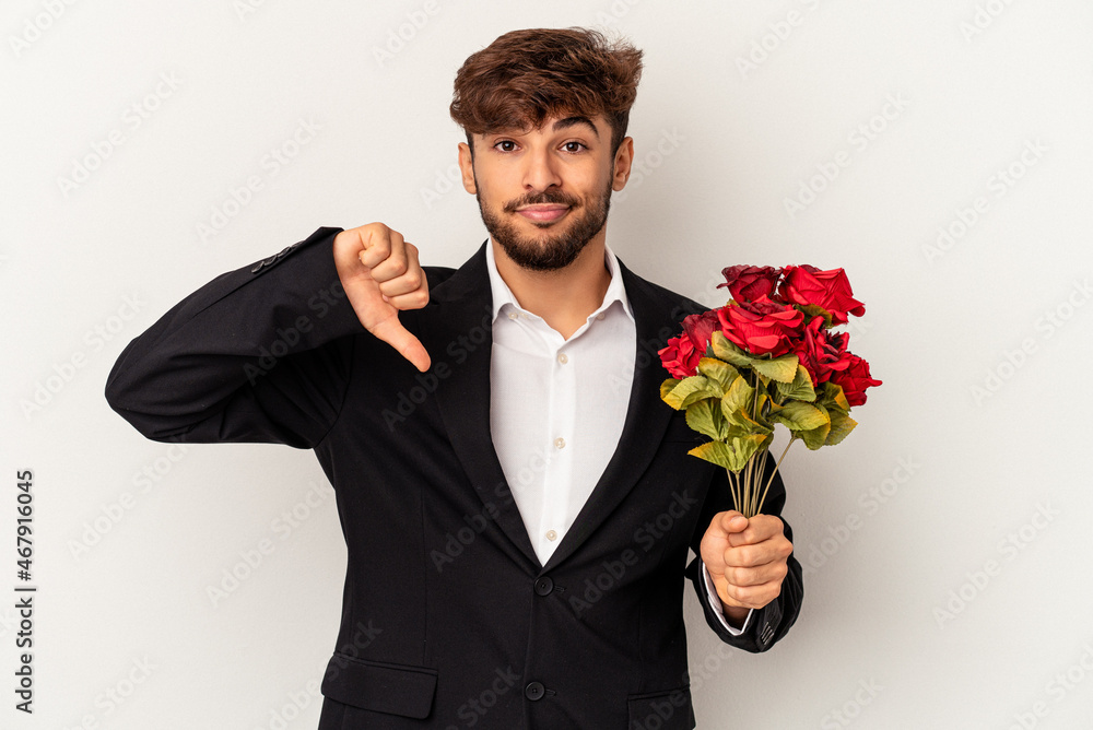 Young mixed race man holding bouquet of roses isolated on white background showing a dislike gesture, thumbs down. Disagreement concept. Young mixed race man holding bouquet of roses isolated on white background showing a dislike gesture, thumbs down. Disagreement concept.