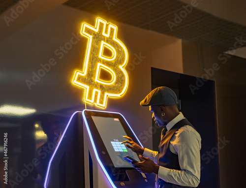 Hombre de negocios consultando su economía en un cajero automático de criptomonedas. photo
