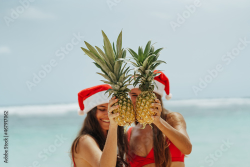 Photography Two beautiful girls holding the pineapple and having fun on the beach, close the face with fruit