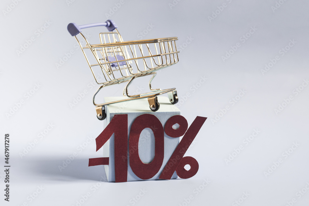 An empty metal basket on a blue podium and the numbers 10% on a blue background close-up. The concept of discounts and sales in trade