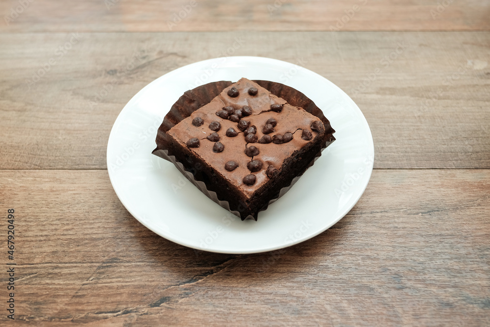 homemade chocolate brownies on a white plate on a brown wooden table. homemade chocolate brownies on a white plate on a brown wooden table.