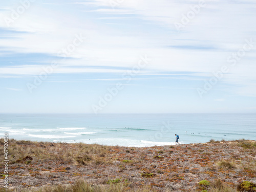 hiker walking relaxed on the fishermen's trail in Portugal with surfers in the background
