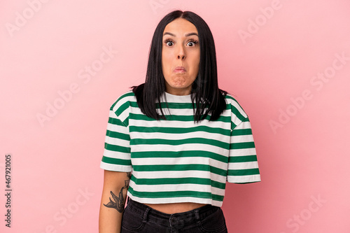 Young caucasian woman with one arm isolated on pink background shrugs shoulders and open eyes confused. © Asier
