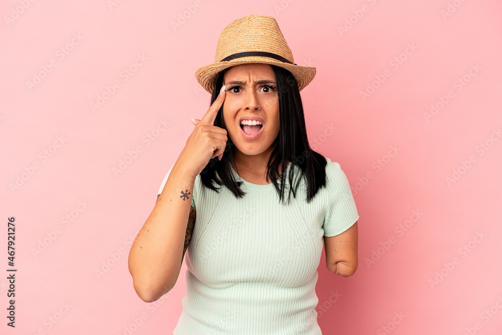 Young caucasian woman with one arm wearing a summer hat isolated on pink background showing a disappointment gesture with forefinger. Young caucasian woman with one arm wearing a summer hat isolated on pink background showing a disappointment gesture with forefinger.