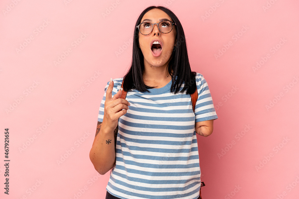 Young caucasian student woman with one arm isolated on pink background pointing upside with opened mouth. Young caucasian student woman with one arm isolated on pink background pointing upside with opened mouth.