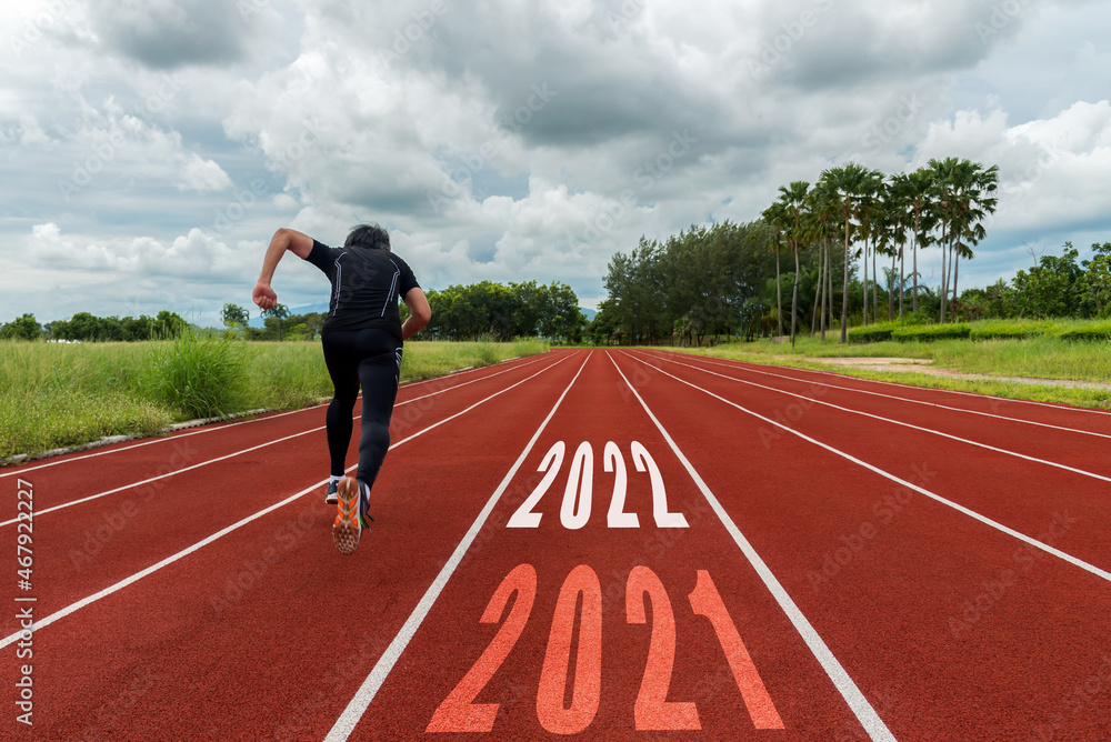 The start into the new year 2022. Start up of runner man running on race track go to Goal of Success. People running as part of Number 2022. Holiday sport and health care Concept The start into the new year 2022. Start up of runner man running on race track go to Goal of Success. People running as part of Number 2022. Holiday sport and health care Concept