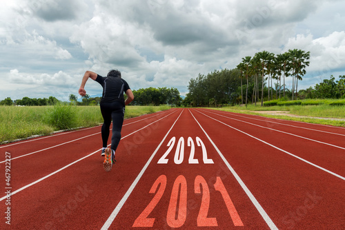 The start into the new year 2022. Start up of runner man running on race track go to Goal of Success.  People running as part of Number 2022.  Holiday sport and health care Concept