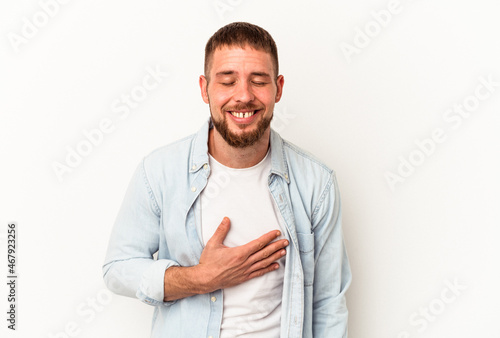 Young caucasian man with diastema isolated on white background laughs out loudly keeping hand on chest.