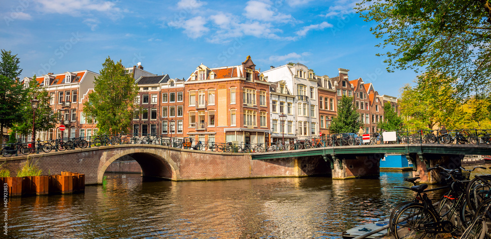Naklejka premium Amsterdam downtown -canals, old houses and a bridge. Nice view of the famous city of Amsterdam. Travel to Europe.